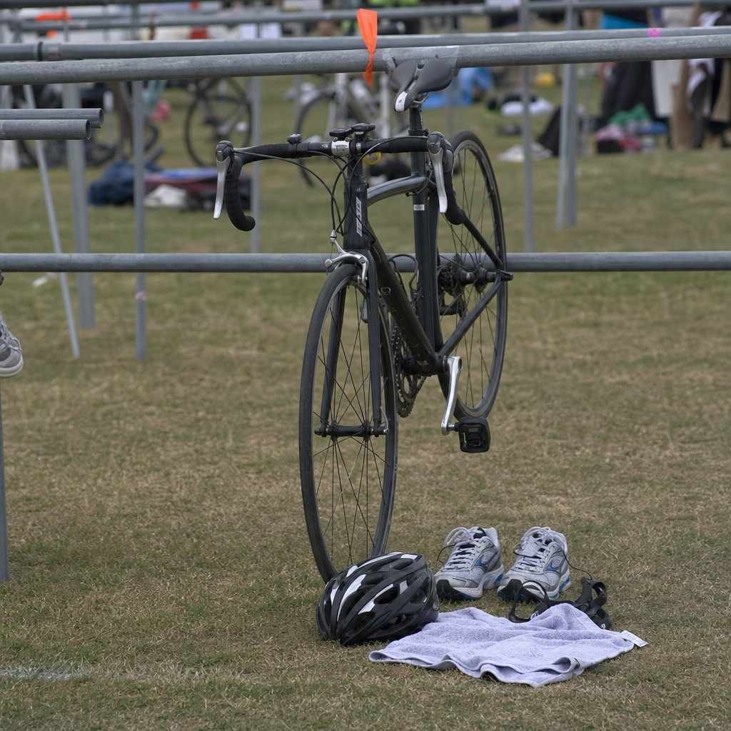 a road bike racked with running shoes and a helmet laid on the ground beside it