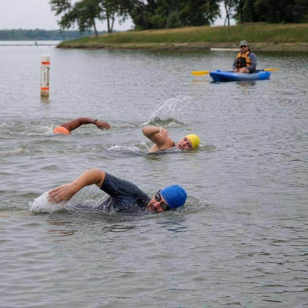 a few swimmers practicing in calm supervised open water near a grassy bank